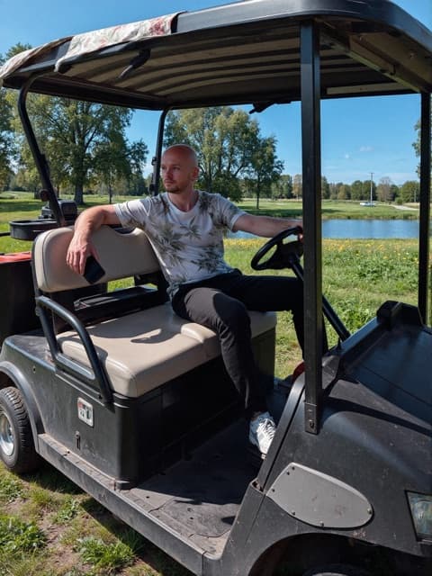 AI-generated dating profile photo: man sitting in a golf cart on a sunny course